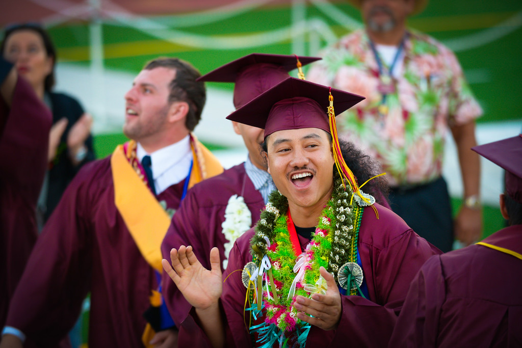 young male grad waving