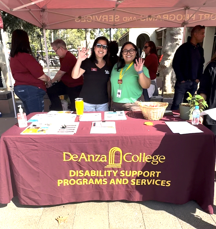 two women waving from Disability Support tent