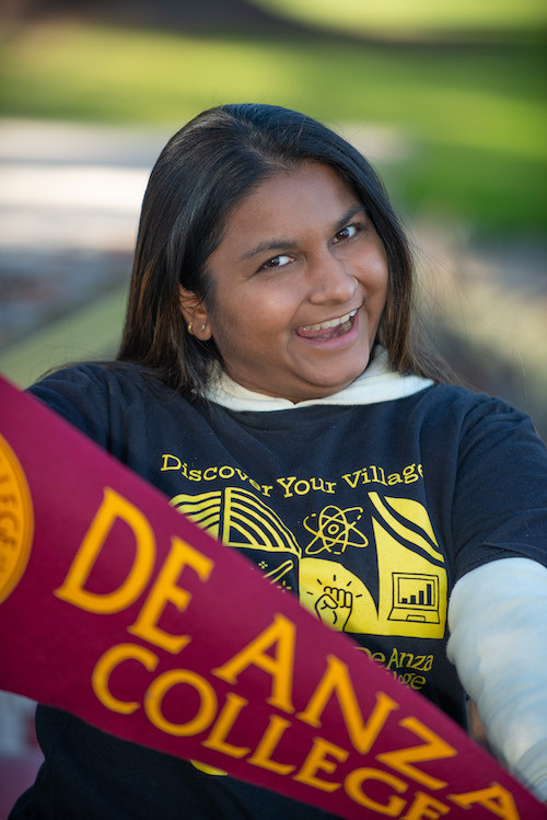 young woman in Villages T-shirt with De Anza pennant